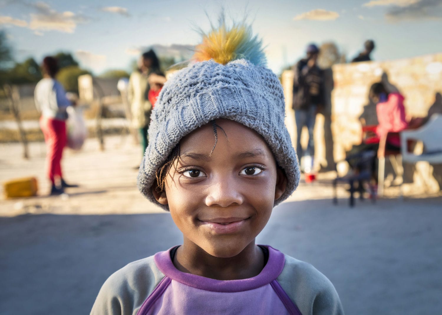 Portrait of a smiling african girl in the village with the family at sunset